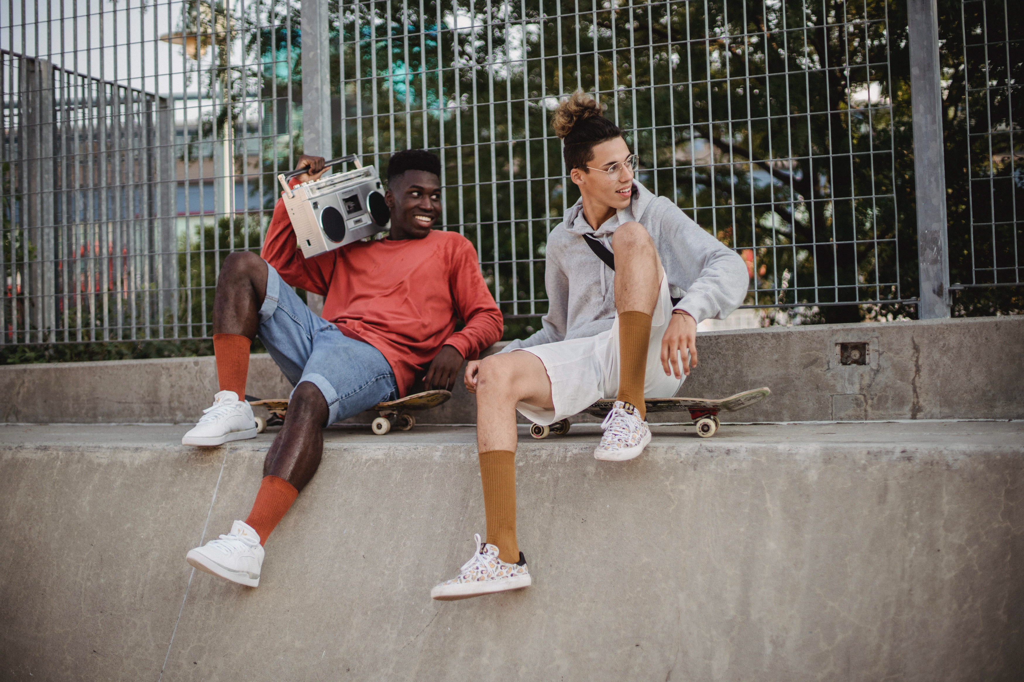Image of Two Men sitting on a concrete wall with a boombox. 
